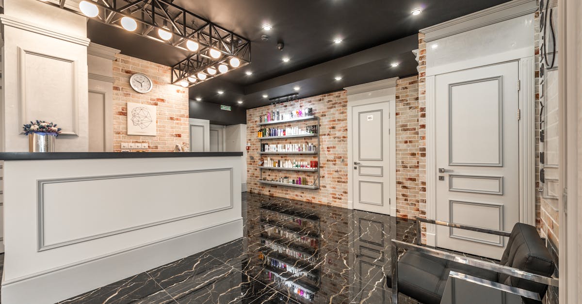 White reception counter with flowers placed in stylish beauty salon with doors and shelves with various cosmetology supplies at brick wall
