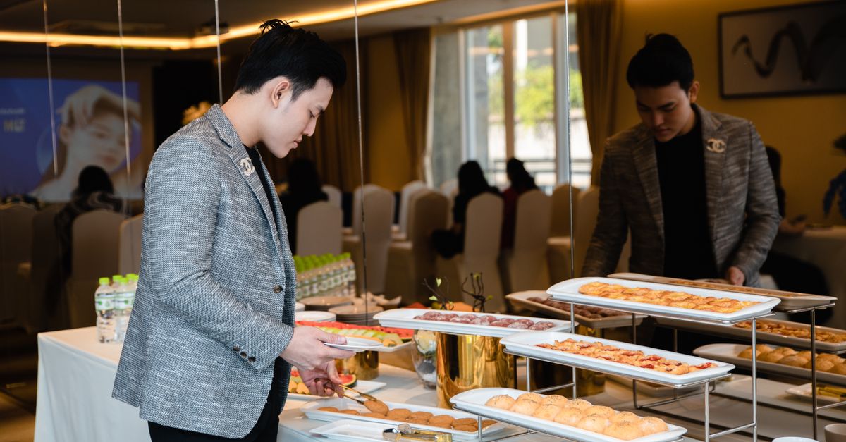 Man selecting pastries from a buffet at a corporate event indoors.
