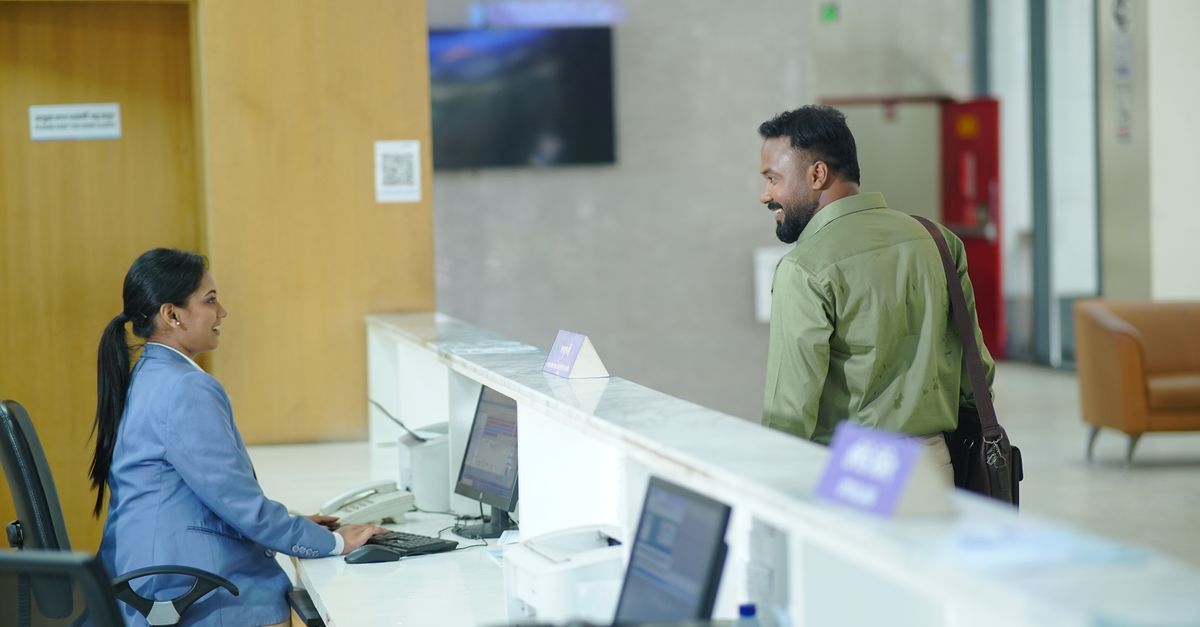 A receptionist assists a guest at the reception desk in a modern hotel lobby in Dhaka, Bangladesh.