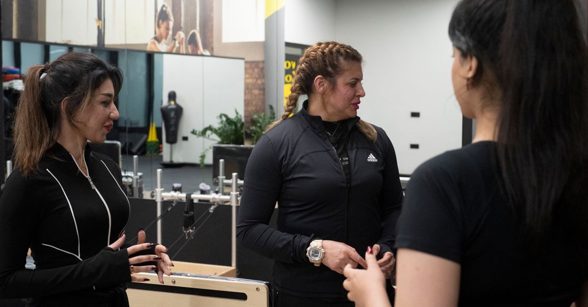 Three women in a modern gym having a conversation. Fitness and wellness theme.