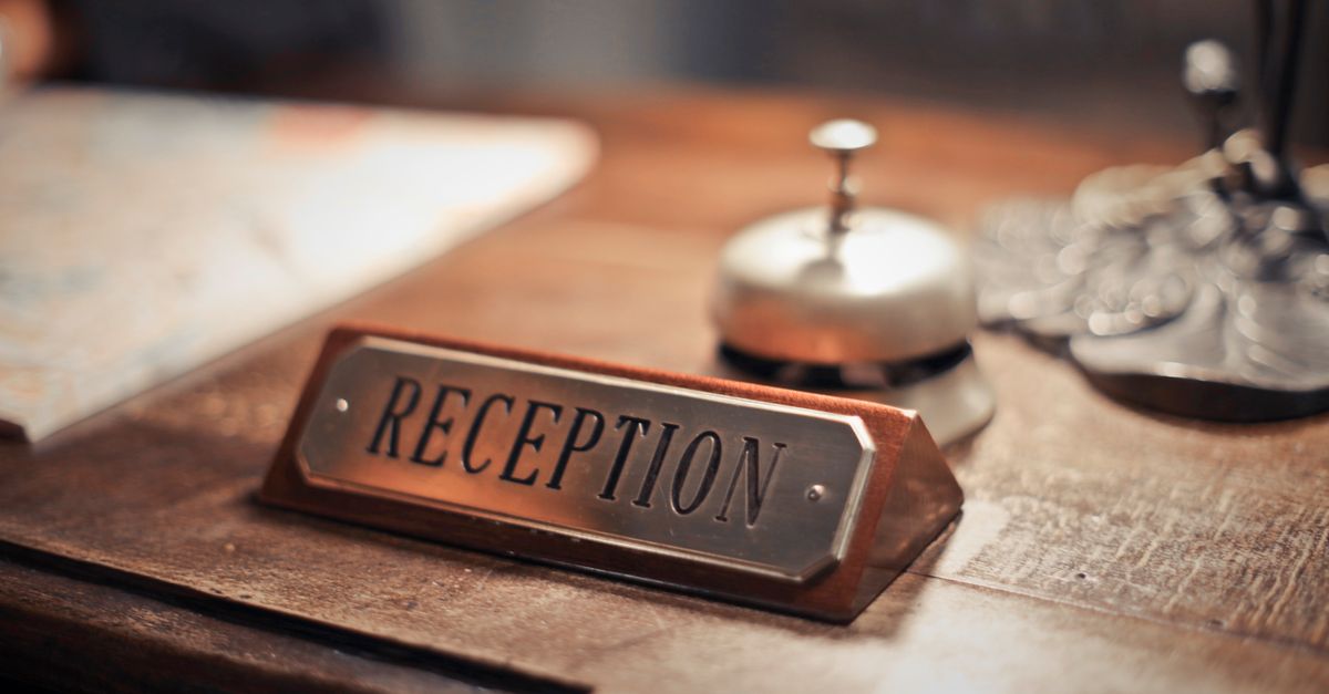 Close-up of a hotel reception desk showcasing a service bell and signage, emphasizing hospitality.