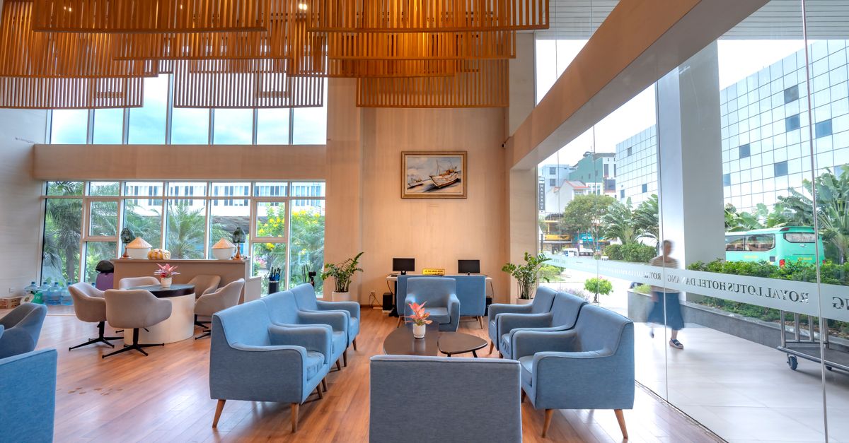 Bright hotel lobby with modern design, blue sofas, and wooden elements.
