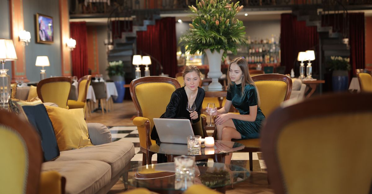 Two women enjoying a conversation in a luxurious hotel lounge, surrounded by elegant decor.