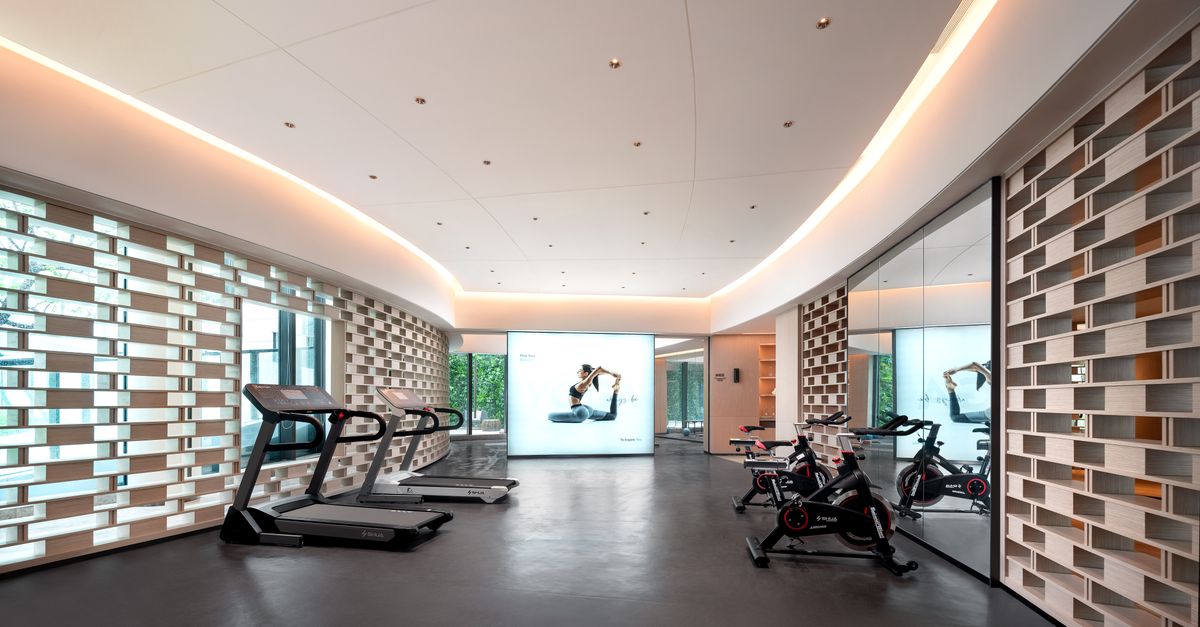 Sleek gym interior with treadmills and stationary bikes, technology-focused design.