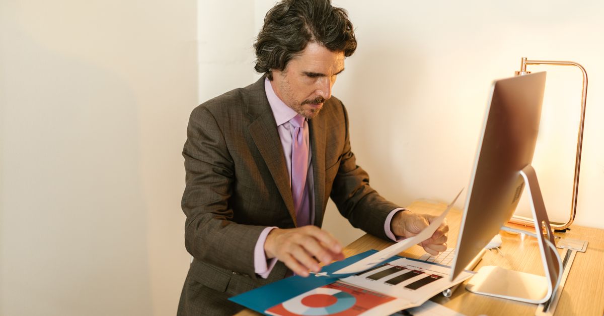 Businessman in suit reviewing financial documents in modern office space.
