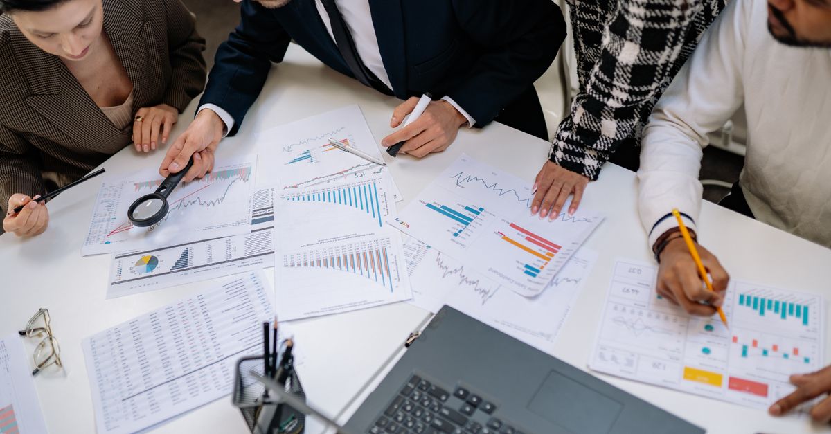 A group of professionals reviewing financial charts in an office meeting setting.