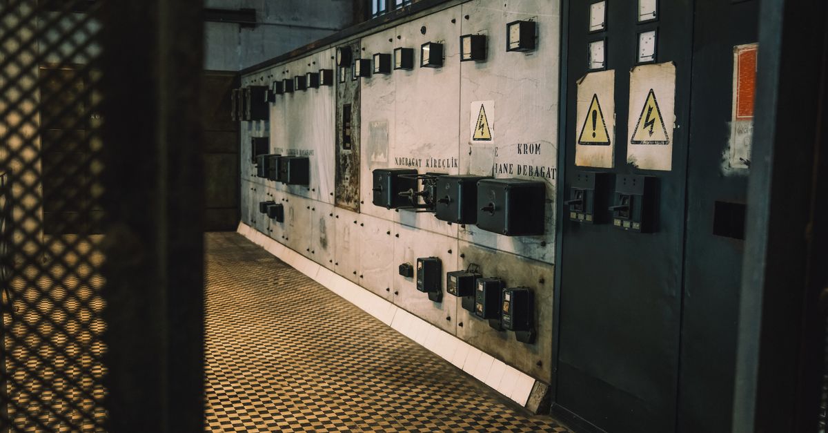 Vintage industrial control panel with warning signs in a dimly lit room, creating a moody atmosphere.
