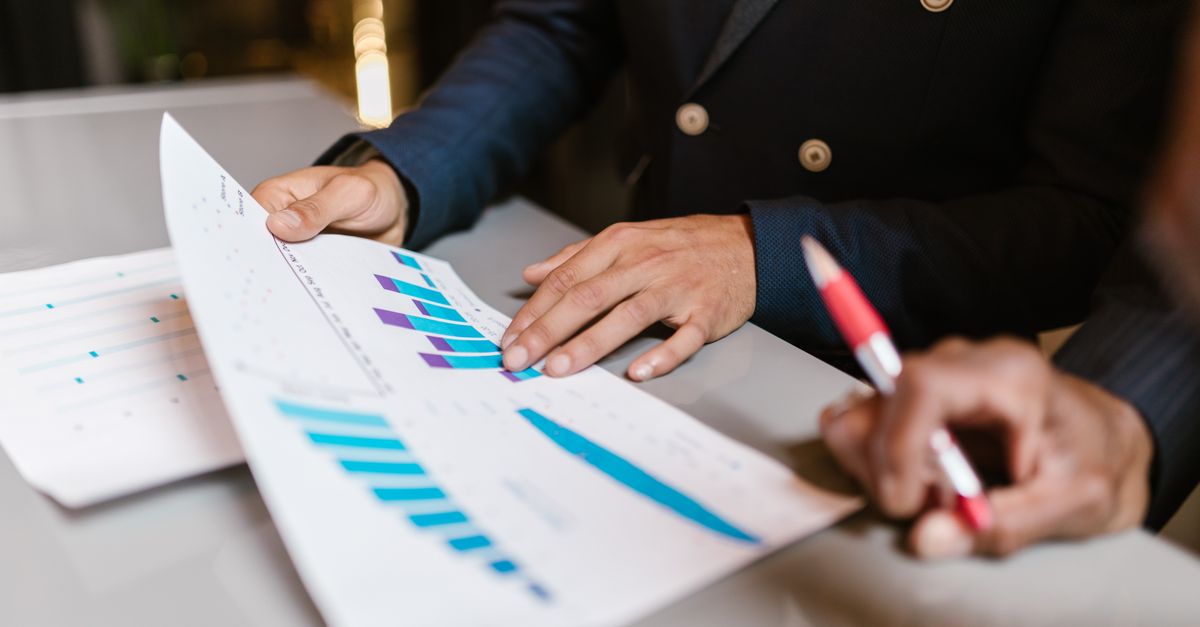 Close-up of professionals reviewing financial graphs at a business meeting.
