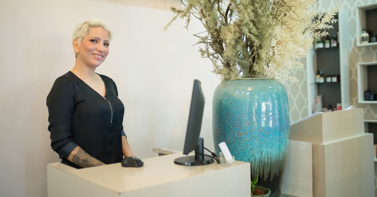 Friendly female receptionist at a stylish hair salon front desk in Portugal.