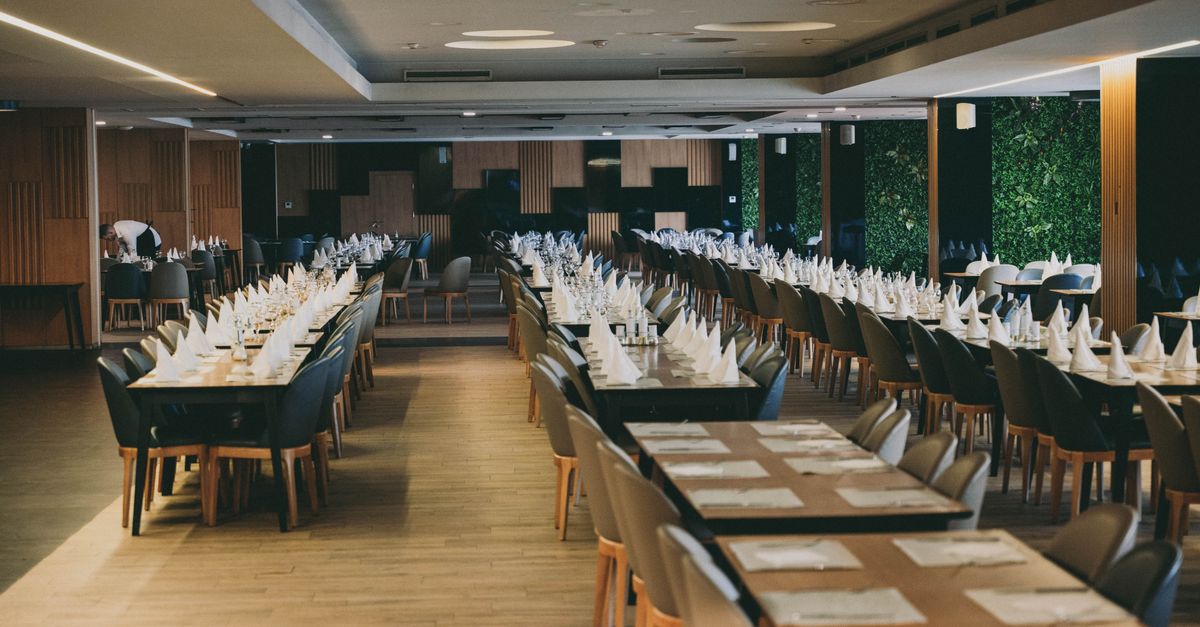 Spacious hotel restaurant interior with neatly arranged formal table settings ready for a grand event.