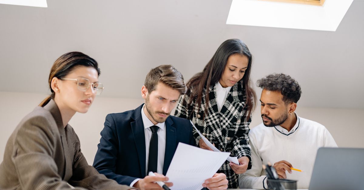 Diverse team working together in an office, discussing documents and strategies.