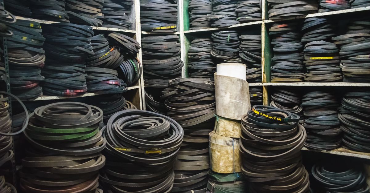 A cluttered storage room filled with stacks of rubber belts and industrial equipment.