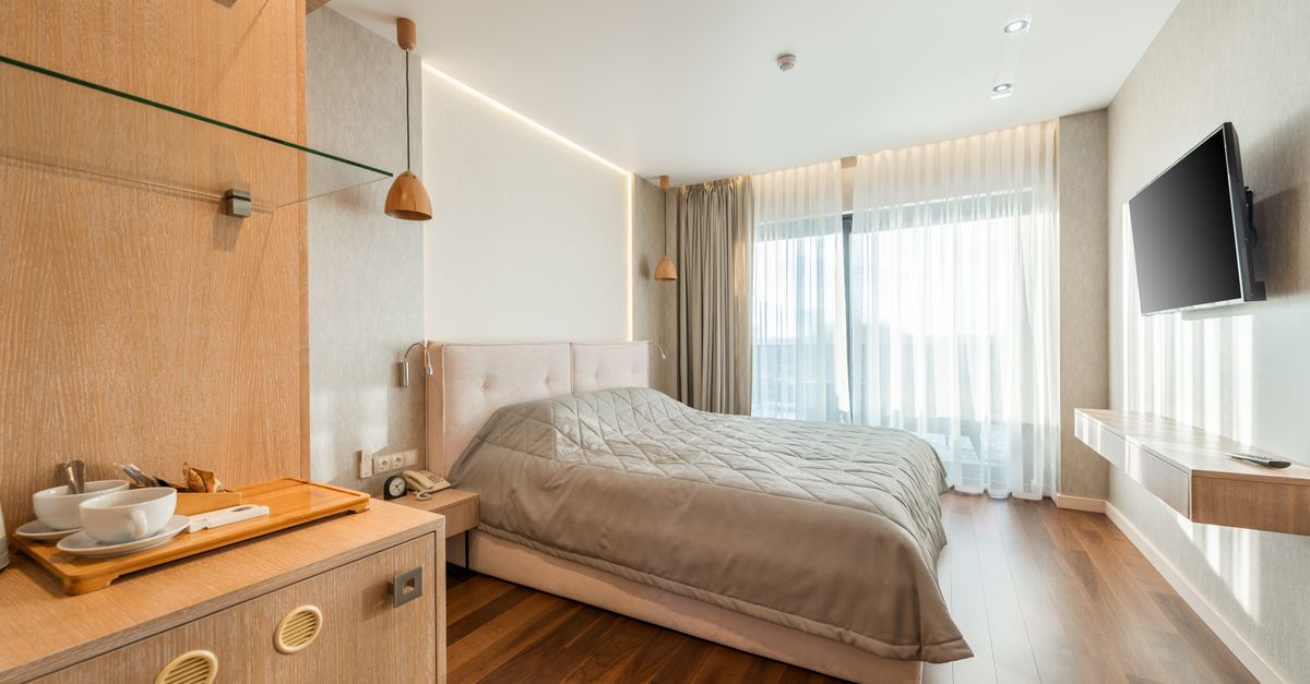 Interior of comfortable bed covered with blanket in bedroom suite in hotel in daylight