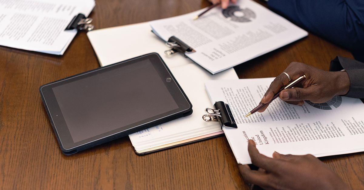 A business meeting with tablets and documents, showcasing digital integration in a professional setting.