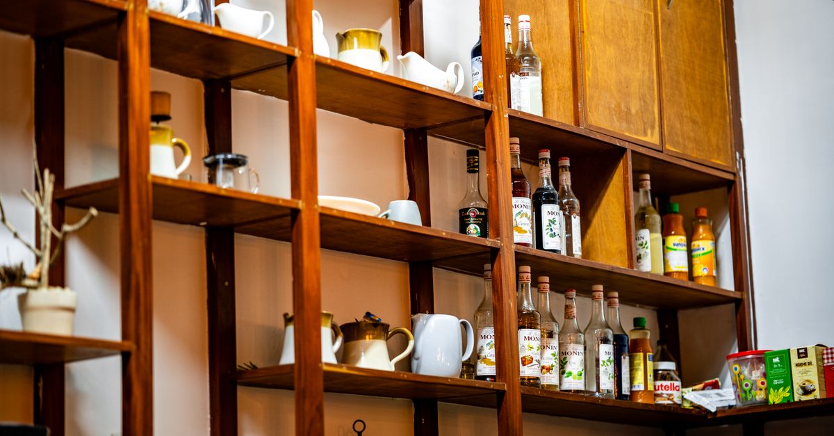 A well-organized café shelf with assorted bottles and mugs, highlighting interior design elements.
