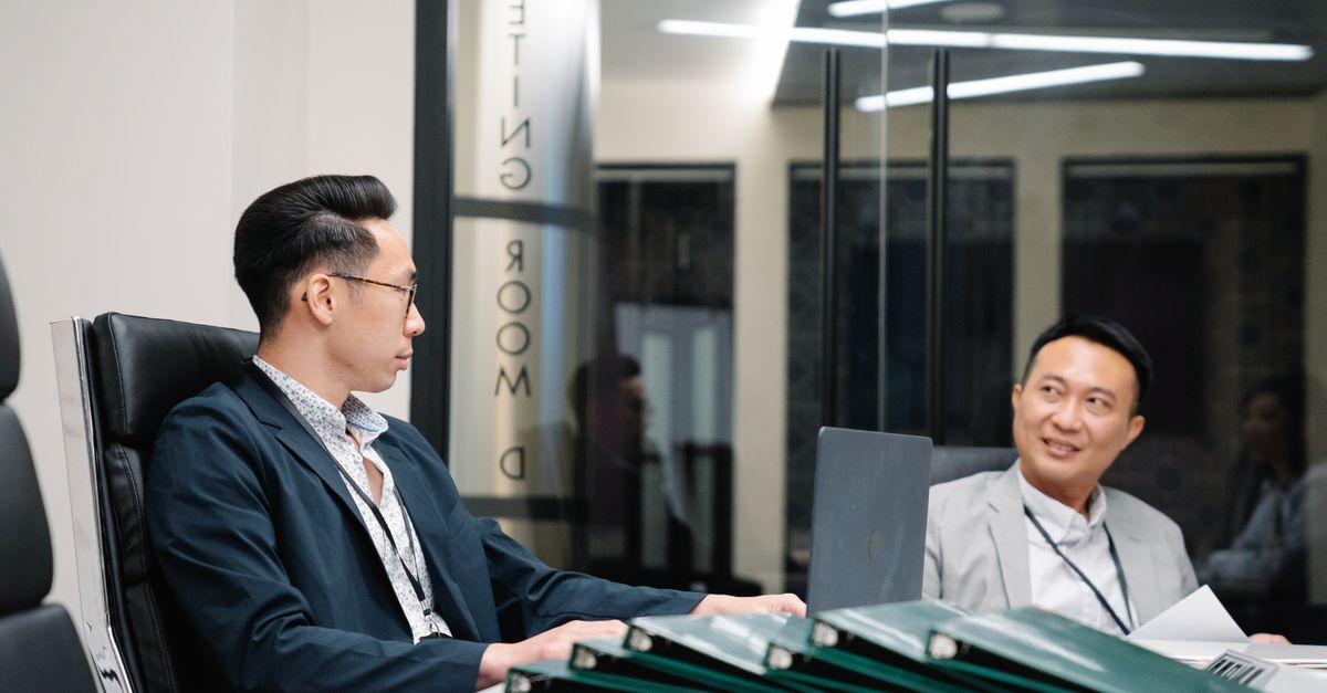 Two businessmen discussing strategies in a modern office meeting room.