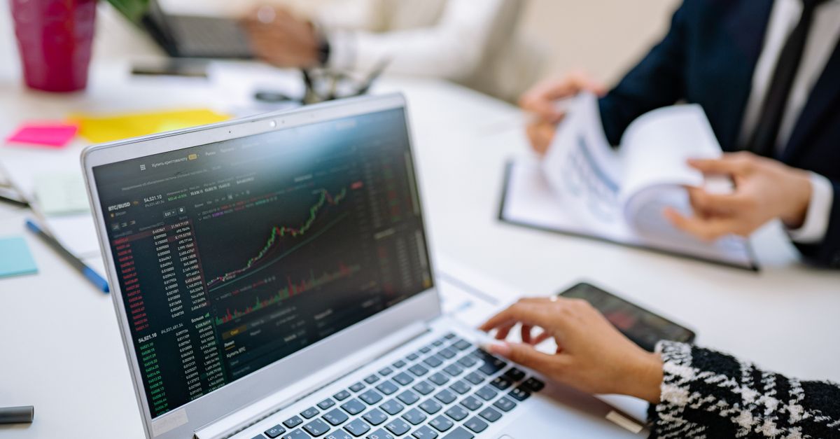 Business team analyzes cryptocurrency market trends using a laptop with graphs and data.