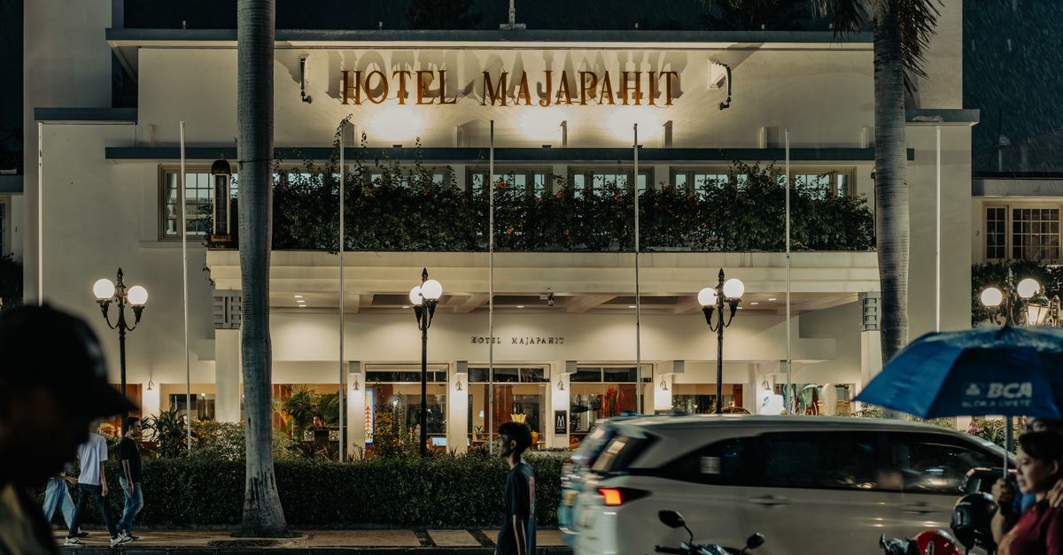 Night view of the historic Hotel Majapahit in Surabaya, featuring street activity and vibrant lights.