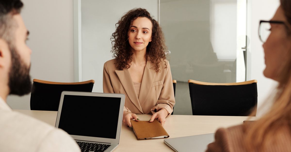 A woman in a business suit participates in a job interview, showcasing professionalism and modern office environment.