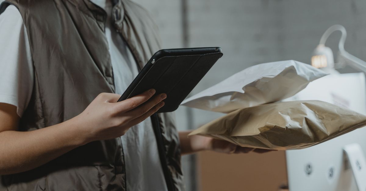 A person using a tablet to manage packages in an indoor setting, highlighting technology and logistics.